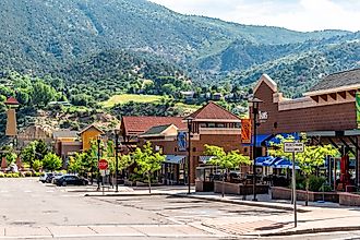 Shopping meadows mall park buildings stores in Colorado town near red mountain and cars parked