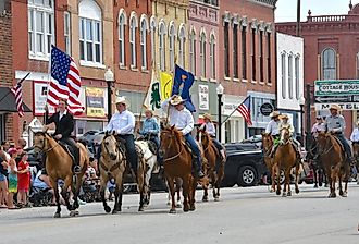 Members of the Local 4H club ride their horses on Main Street in the Washunga Days Parade, Council Grove. Image credit mark reinstein via Shutterstock.