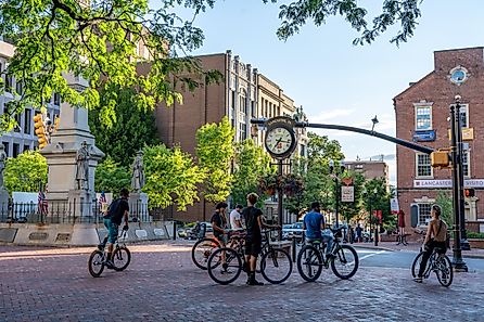 A group of male teenagers riding bikes on the city sidewalk.