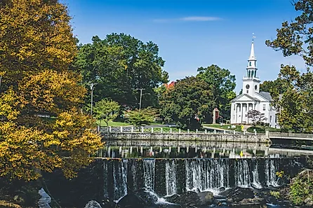 View of white church and waterfall surrounded by trees in Milford, Connecticut