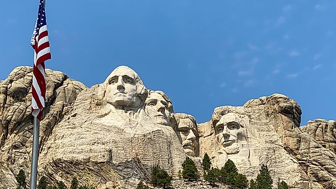 Mount Rushmore with the American flag waving in the foreground.