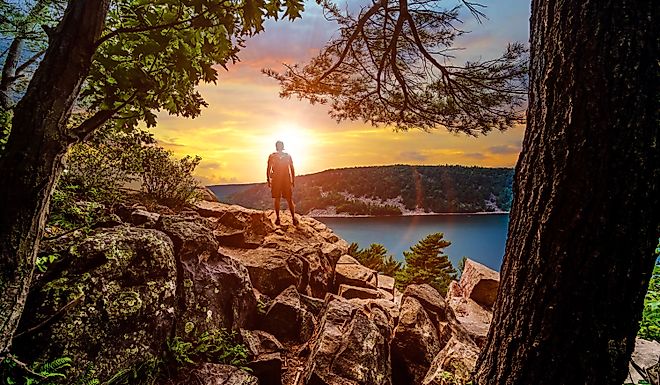 A silhouette of a man looking out into the sunset over Devils Lake State Park from a hiking viewpoint in Baraboo, Wisconsin USA.