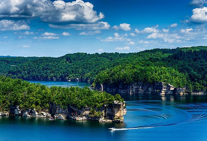 Aerial view of Summersville Lake, with boat turning at Long Point and blue skies.