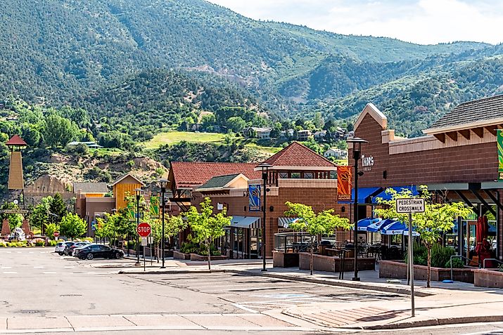 Shopping meadows mall park buildings stores in Colorado town near red mountain and cars parked