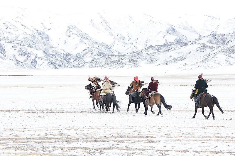 Golden eagle festival during the winter in Ulgi Mongolia local men riding on horses around the mountains covered with snow.