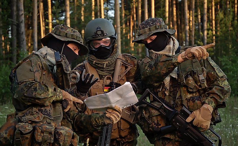 Three german soldiers discuss a plan of action. Coordinate the team.