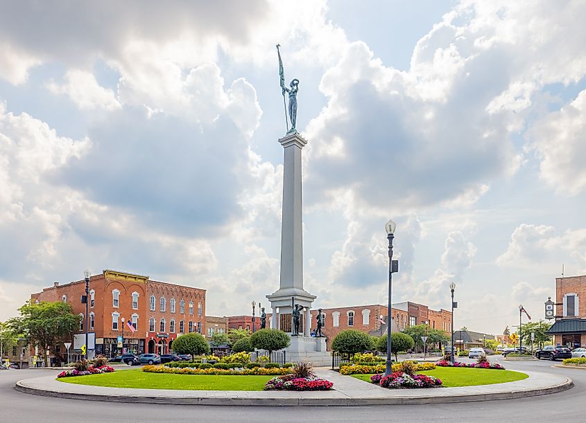 The Steuben County Soldiers Monument in downtown Angola, Indiana, with historic business district buildings in the background.