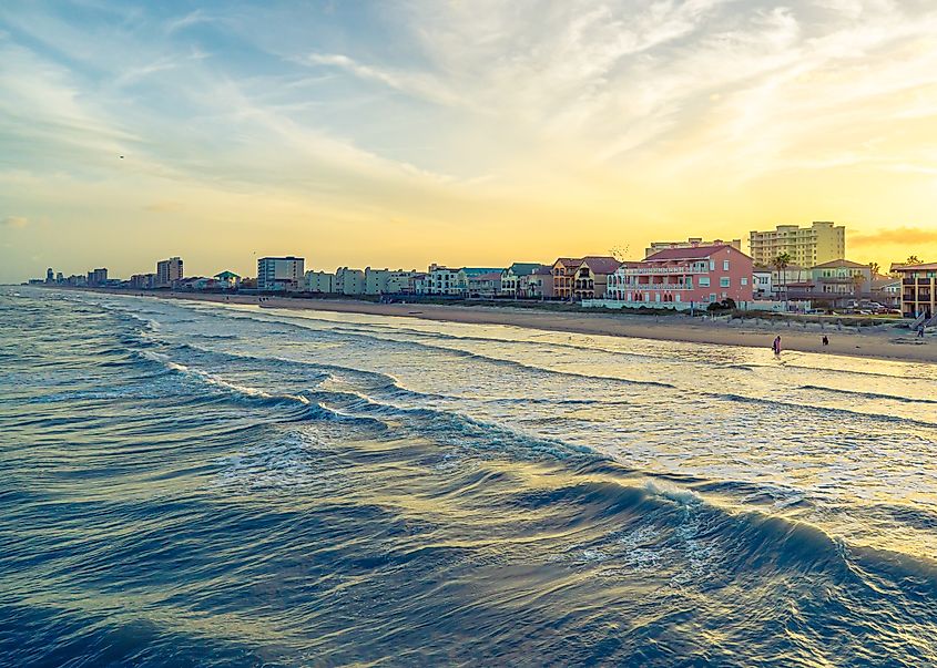 Sunset on South Padre Island, with the sun dipping below the horizon and casting a warm glow over the ocean and sandy beach.