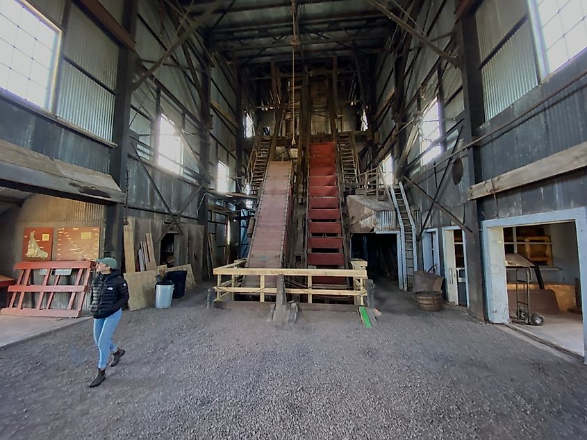 A woman looks around the inside of a tall mining shift/hoist.
