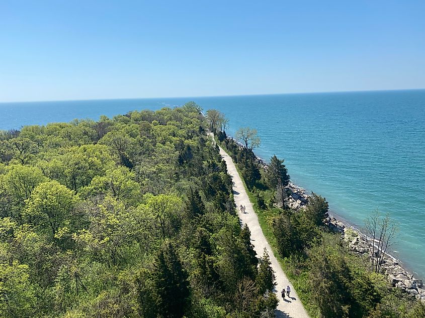 A bird's-eye-view of a forested peninsula lined with a pedestrian path.