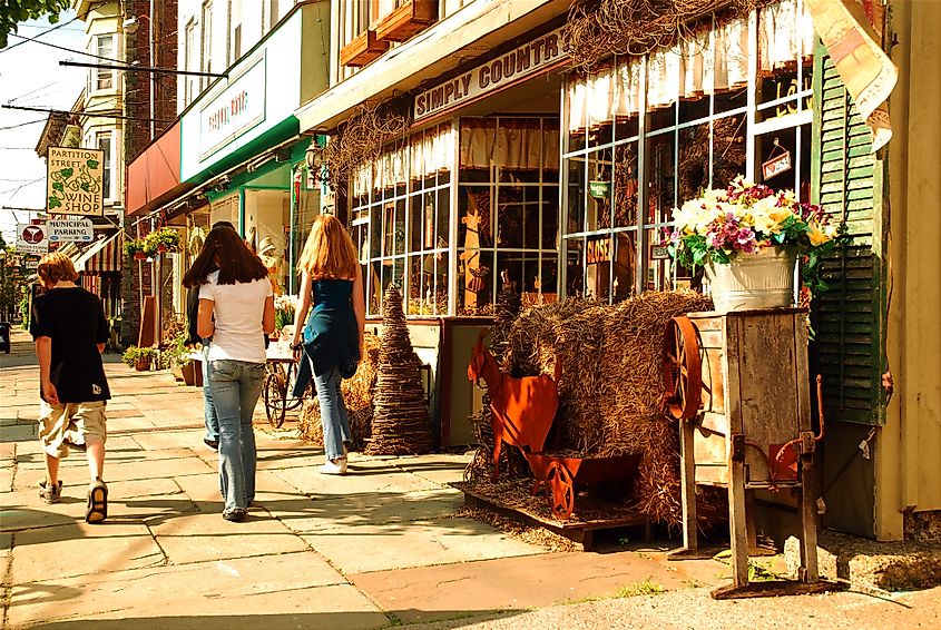 Three teenagers walking past a home decor store in downtown Saugerties, New York, known for its vibrant, small-town charm.