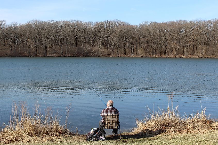 Man in a flannel shirt fishing at Horsetail Lake in Palos Park, Illinois