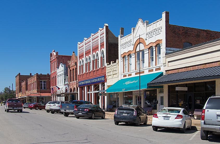 A small downtown street in Lockhart, Texas, lined with parked vehicles and classic storefronts.