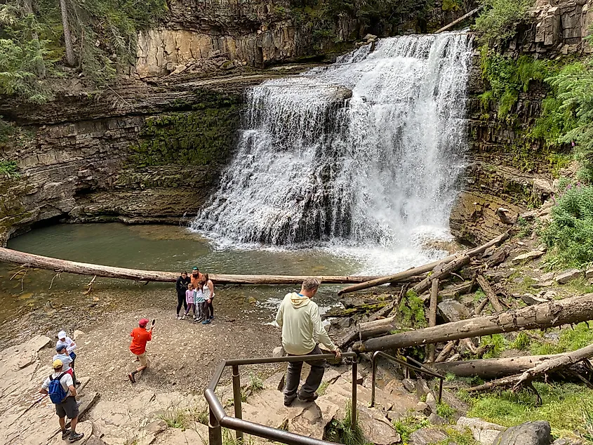 A small group gathers at the base of a rushing waterfall.