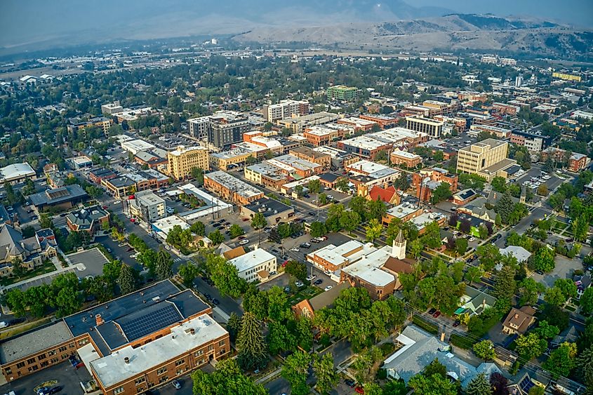 Aerial view of downtown Bozeman, Montana, in summer, showcasing buildings, streets, and the surrounding landscape.