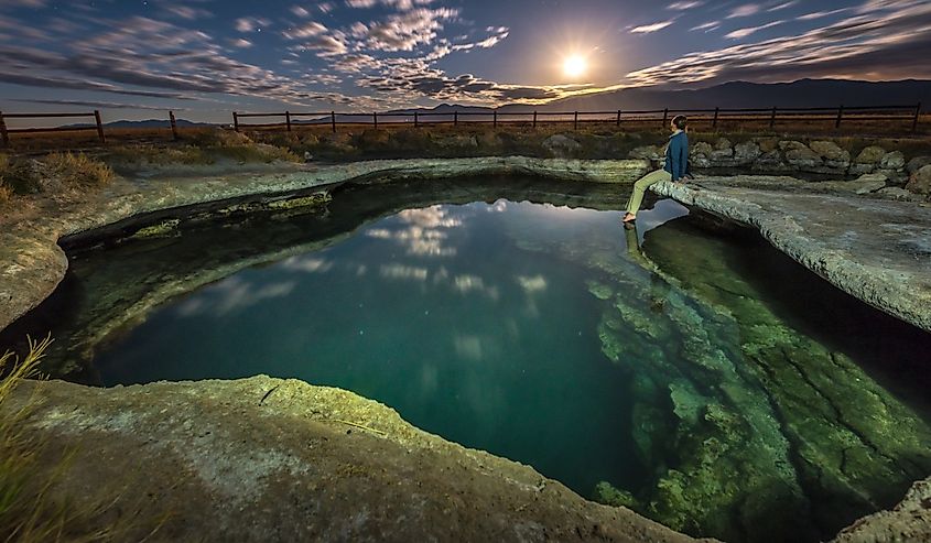 Girl sitting over Meadow Hot Spring looking at the moon