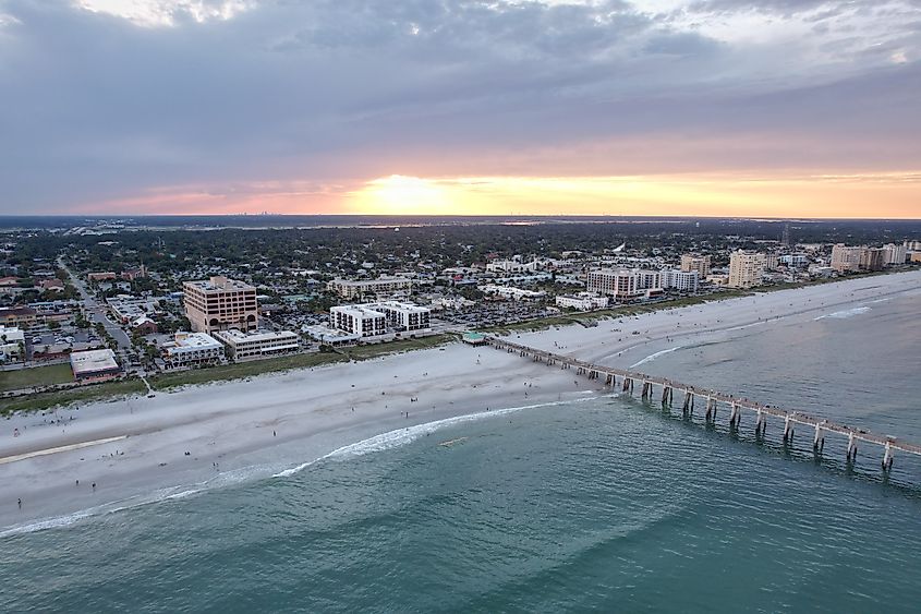 Aerial view of Jacksonville Beach, Florida, at sunset, showcasing the coastline, sandy beach, and surrounding cityscape bathed in warm evening light.