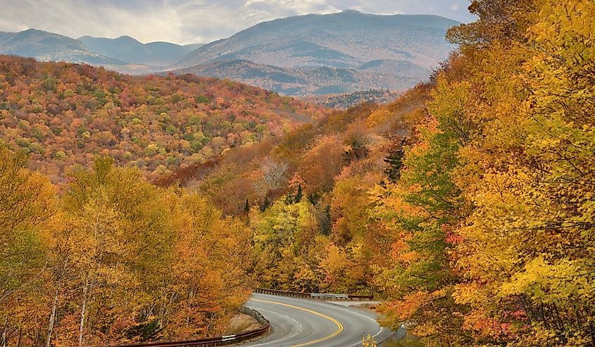 Autumn glory in New England. Stunning view of forest, mountains, and vibrant fall foliage from top of Kinsman Notch in the White Mountains of New Hampshire.