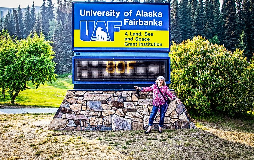 A woman posing before the University of Alaska Fairbanks sign