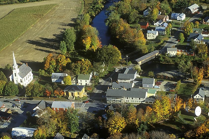 Aerial view of Waitsfield, VT, and the Mad River along Scenic Route 100 during autumn, showcasing vibrant fall foliage and picturesque landscape.