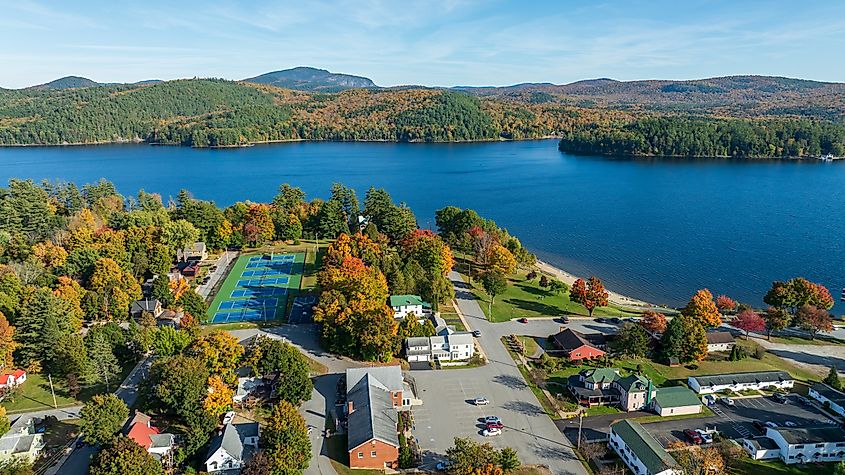 Aerial view of Schroon Lake, New York, showcasing the calm lake, fall foliage, and small town structures.