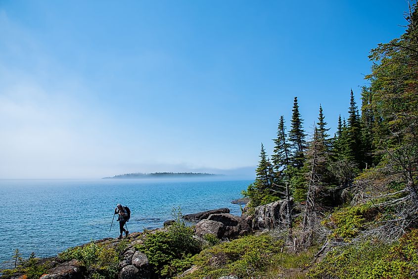 A lone hiker treks through the waterfront woods of Isle Royale National Park.