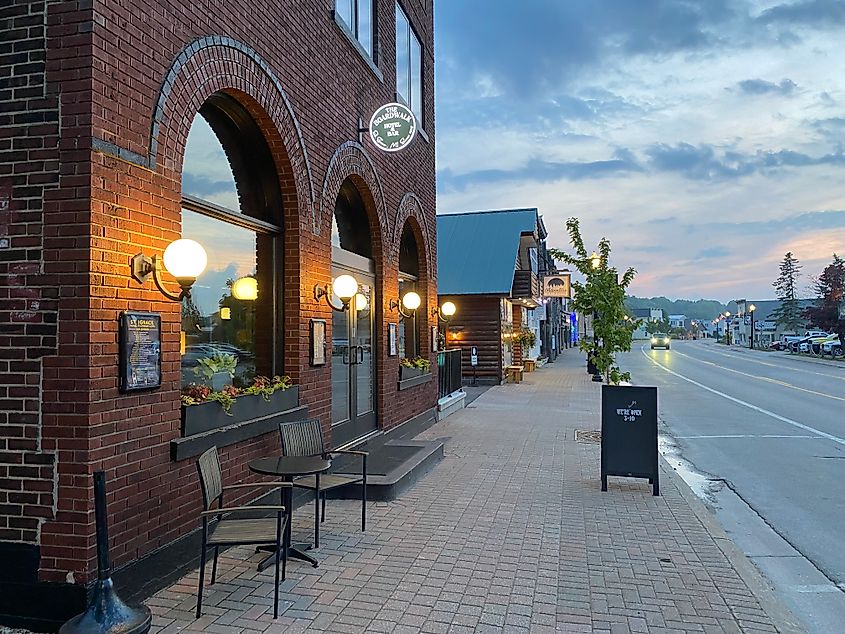 A illuminated, red-brick restaurant in the evening along a sparsely trafficked road.