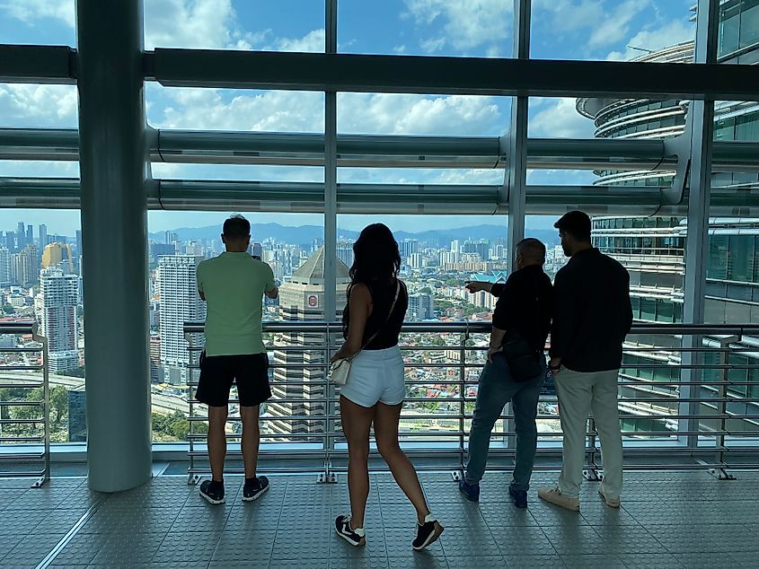 A group of tourists looking out on Kuala Lumpur's skyline from atop the Petronas Towerss Skybridge