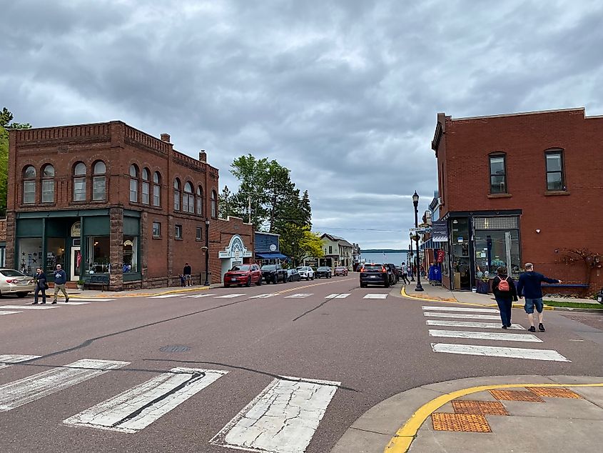 Pairs of pedestrians cross on opposite sides of a crosswalk in the small downtown of Bayfield, WI.