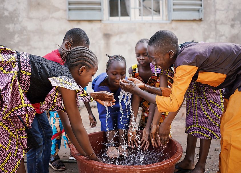 Children playing with and pouring water from bucket in a village in Mali. Shutterstock.