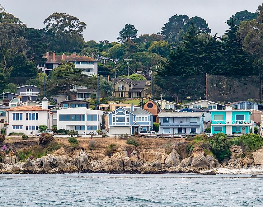 Houses in Pacific Grove, California (in Monterey County) overlook the rocky coastline, as viewed from a passing boat.