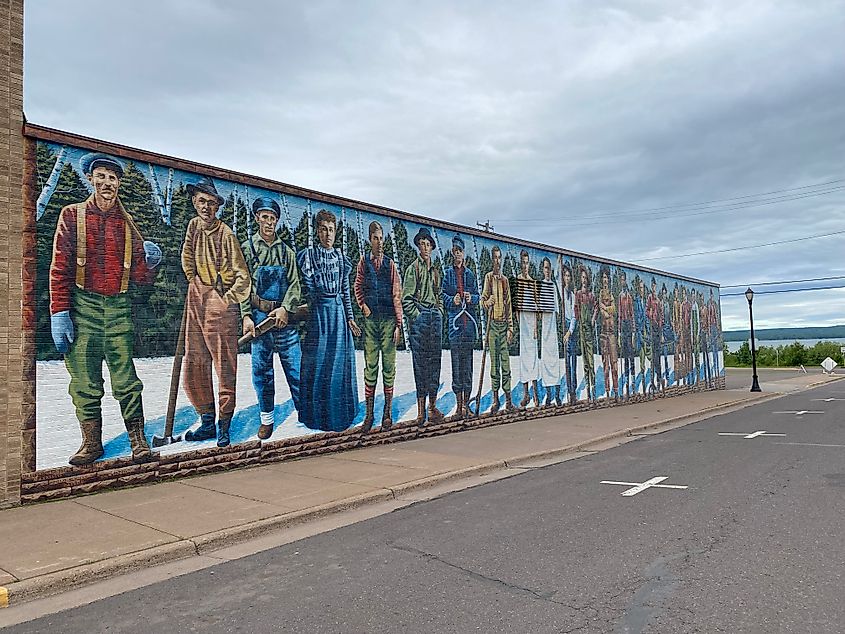 A mural depicting a row of lumberjacks covers the entire side of a building.