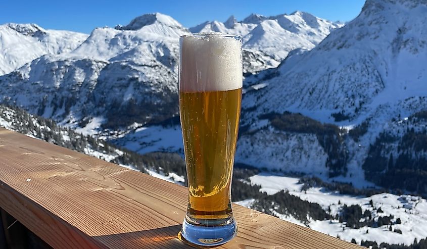 Apres ski in the Austrian Alps. Glass of wheat beer on wooden fence on a sunny day.
