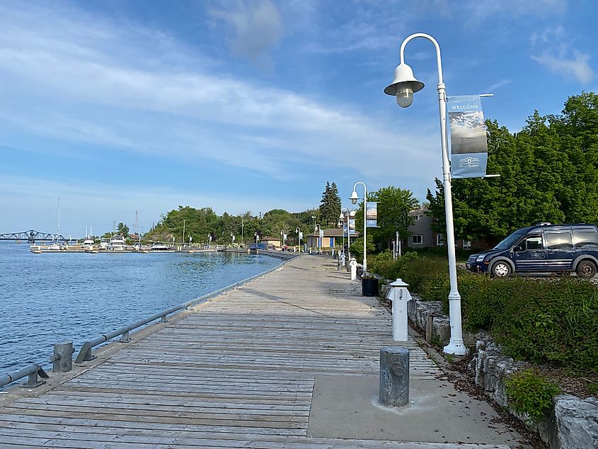 A waterfront boardwalk leads past a blue van and toward an old steel swing bridge