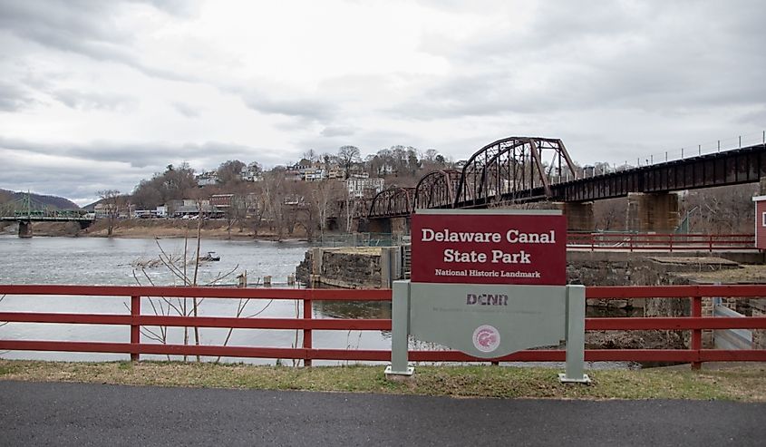 Sign at the Delaware Canal State Park with railroad bridge in background