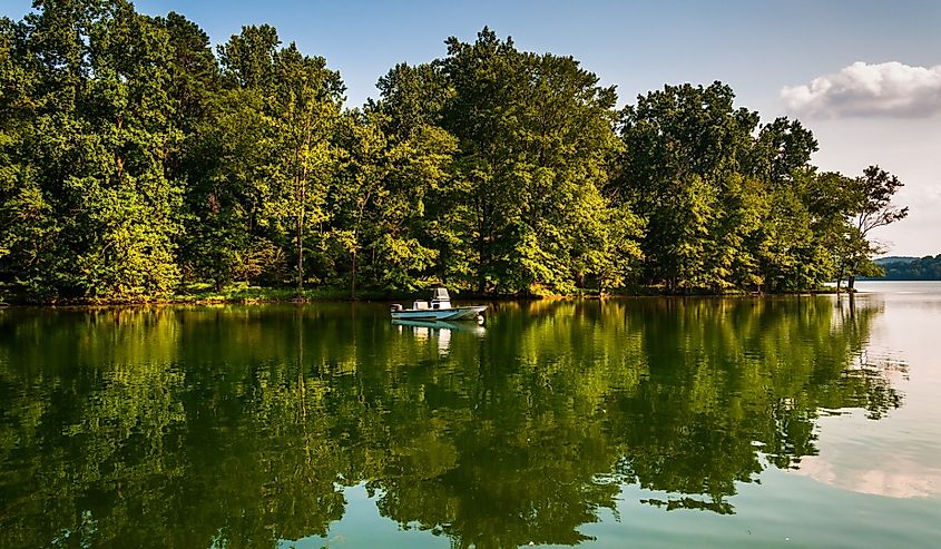 Trees and boat reflecting in Loch Raven Reservoir, near Towson, Maryland.