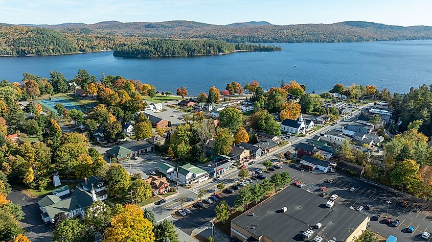 Aerial view of Schroon Lake, New York, with town buildings, colorful autumn foliage, and a peaceful lakeside setting