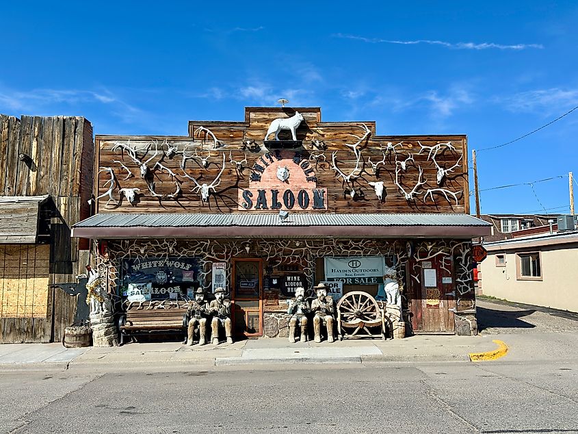 Exterior of White Wolf Saloon in downtown Douglas, Wyoming, featuring a western-style building with numerous antlers attached and carved statues of men outside.