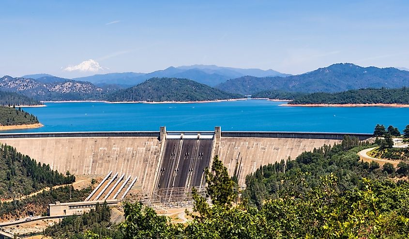 Shasta Dam on a sunny day; the summit of Mt Shasta covered in snow visible in the background; Northern California