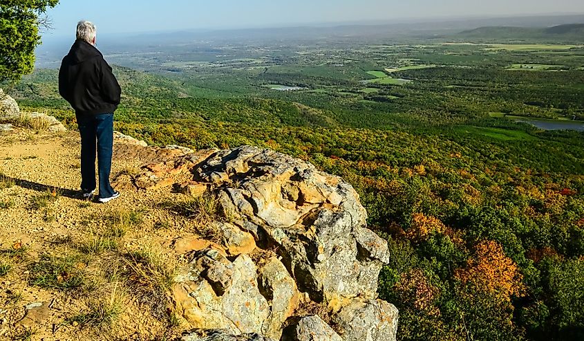 Senior woman looking across the Ozarks of Arkansas landscape from a hiking trail in Mount Magazine State Park.