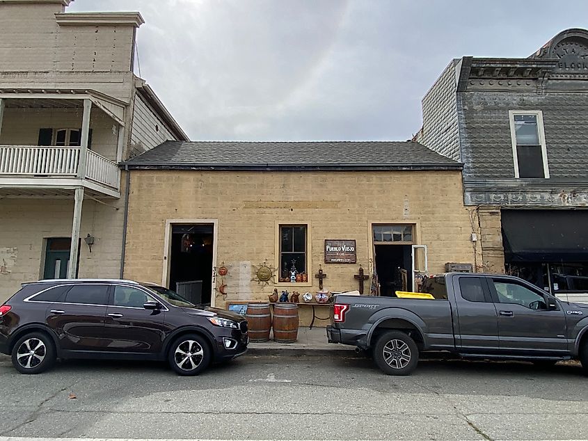A small mexican restaurant in an adobe-style structure, sandwiched between to larger, frontier-style buildings.