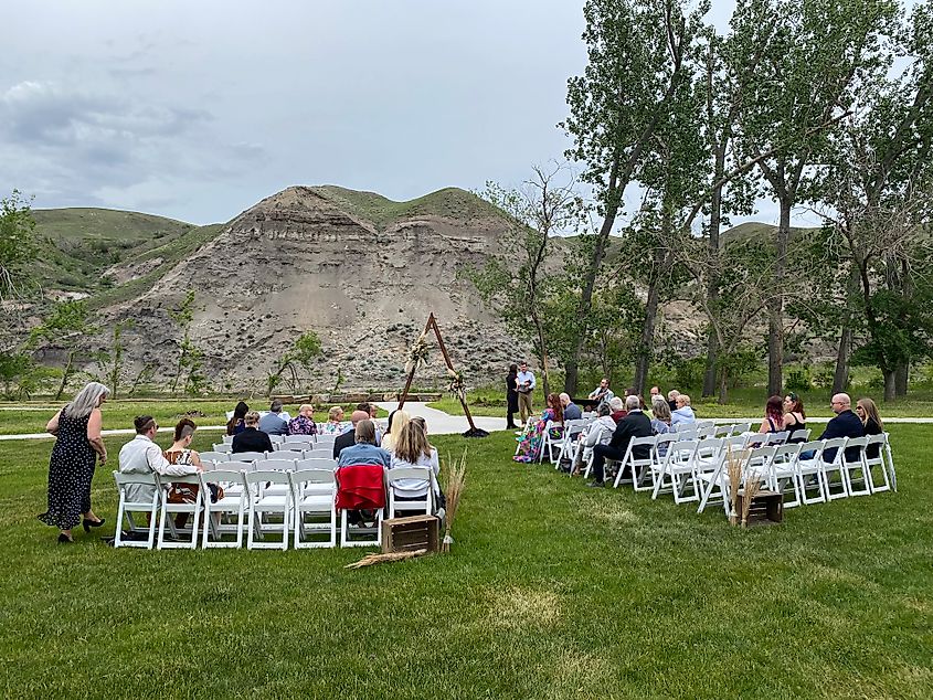 A small wedding ceremony on the banks of a freshly-sod river, backdropped by rolling badlands.