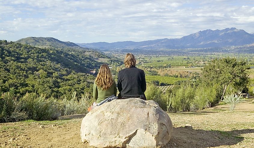 Couple sits and meditates at Meditation Mount's Point overlooking the Ojai Valley, CA