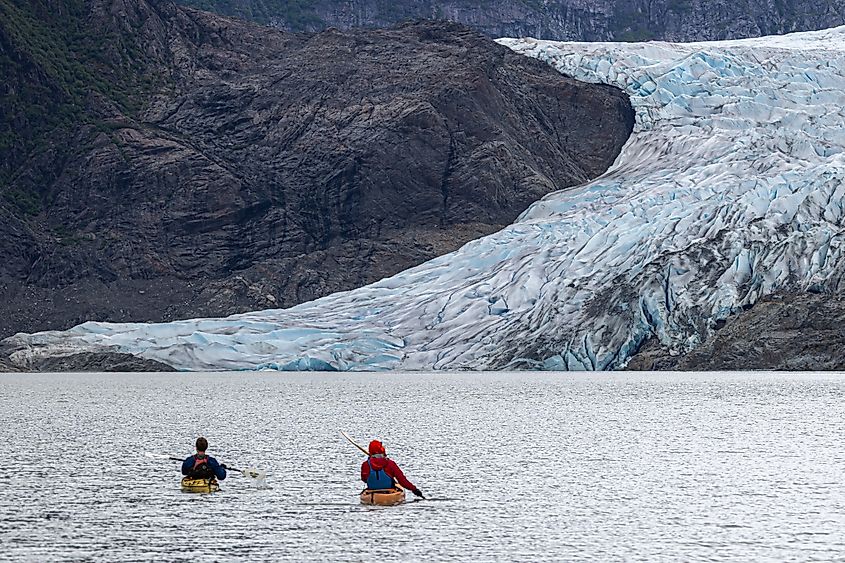 Two kayakers paddling toward Mendenhall Glacier in Alaska.