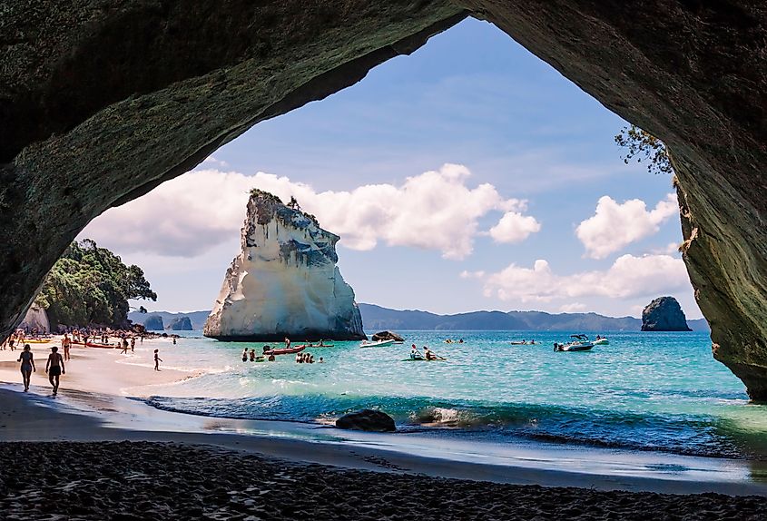 Cathedral Cove, beautiful beach with rocks and tourists in cave in Hahei, New Zealand.