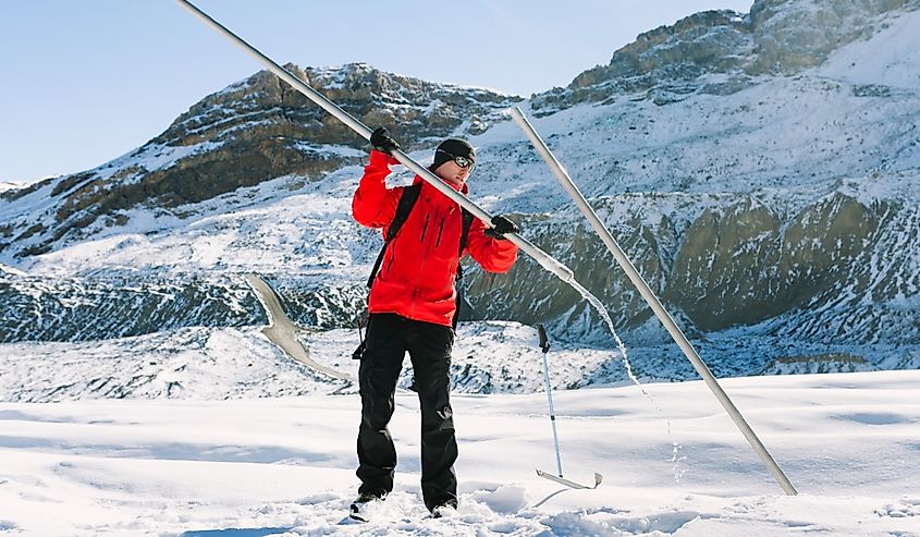 Man on Athabasca glacier uses metal pipes to research Climate Change and measure glacial melt in Banff, Alberta.