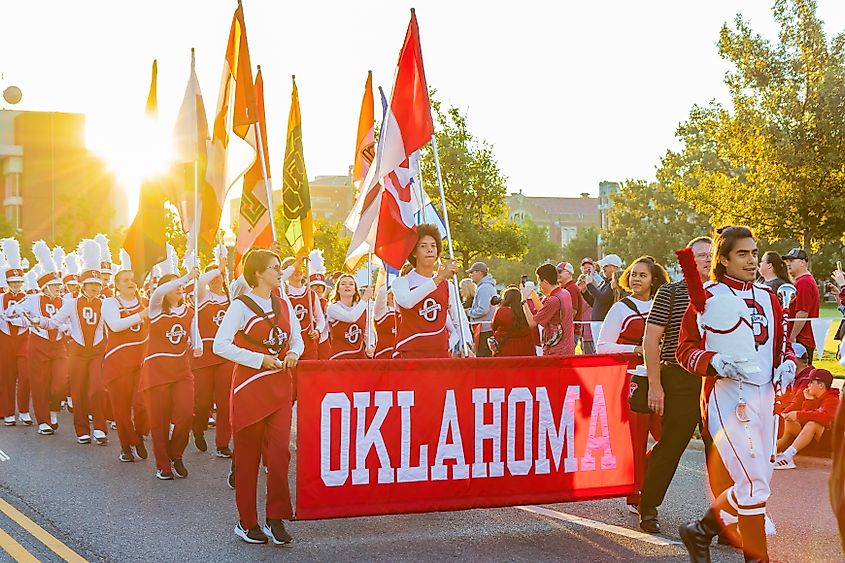 The University of Oklahoma marching band parades down a sunlit street during Homecoming