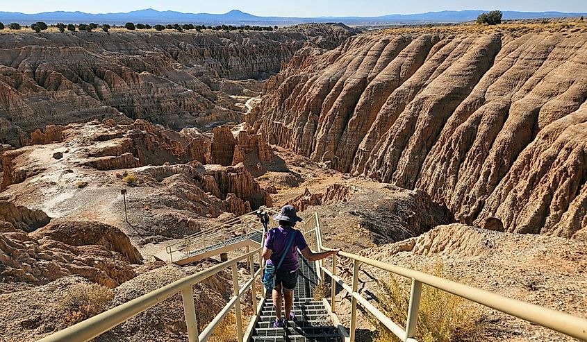 Woman hiking down a staircase into a canyon at Cathedral Gorge State Park, Panaca