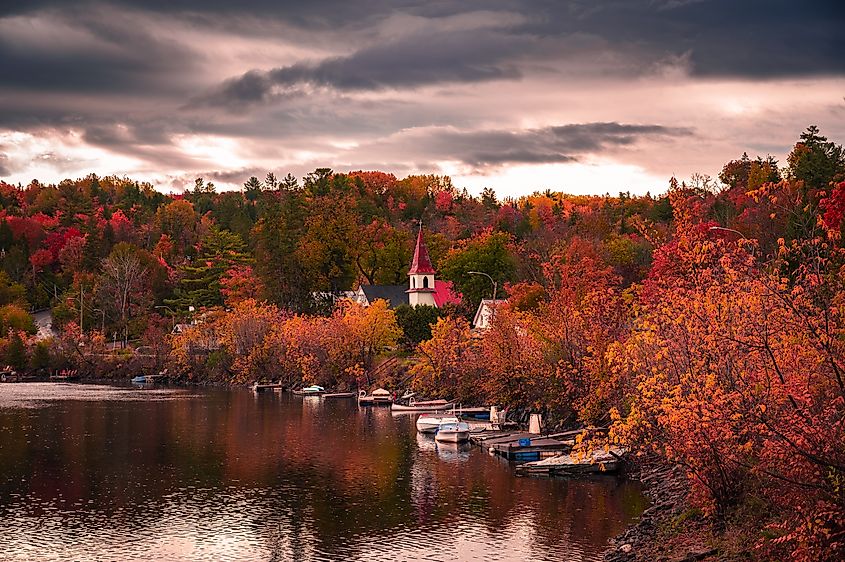 A picturesque autumn scene in the village of Wakefield, Quebec, with boats gently floating on the Gatineau River. 