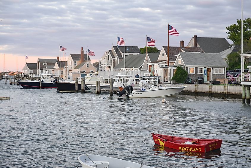 A gray evening at the Easy Street Boat Basin in Nantucket Harbor, with shingled cottages, boats, and six American flags flying proudly.